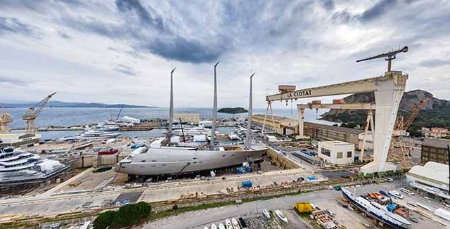 Aerial view of sea dry dock in La Ciotat city, France, the cargo crane, boats on repair, a luxury sail yacht and motor yacht, mountain is on background, shipyard