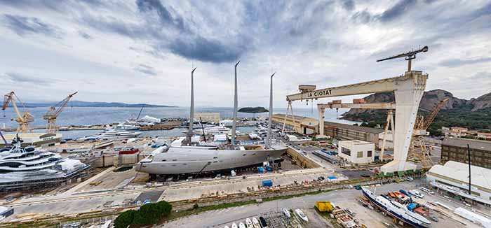 Aerial view of sea dry dock in La Ciotat city, France, the cargo crane, boats on repair, a luxury sail yacht and motor yacht, mountain is on background, shipyard