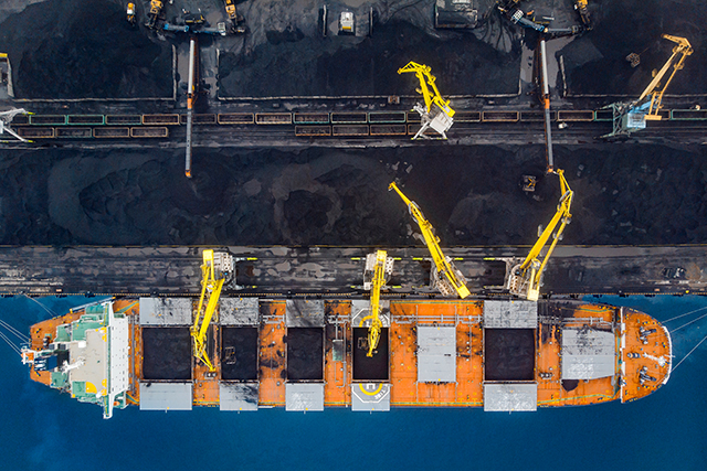 Loading coal anthracite mining in port on cargo tanker ship with crane bucket of train. Aerial top view