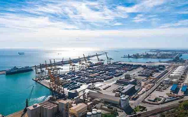 Sunshine on Balearic sea & Barcelona industrial shipping and rail ports on a blue-sky day.