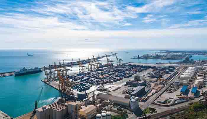 Sunshine on Balearic sea & Barcelona industrial shipping and rail ports on a blue-sky day.