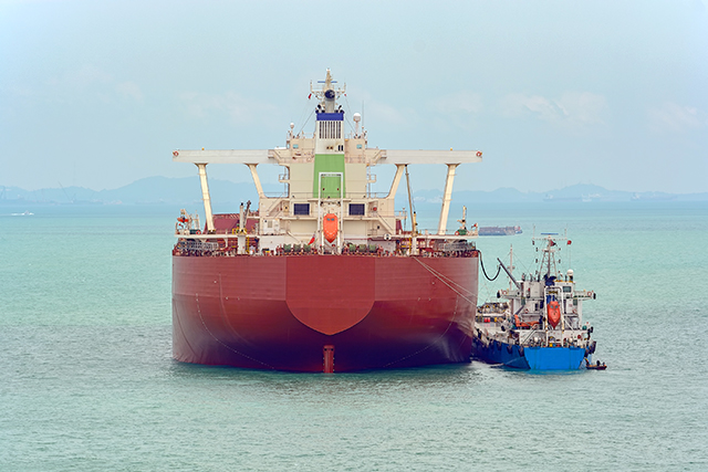 Loading anchored oil supertanker via a ship-to-ship oil transfer